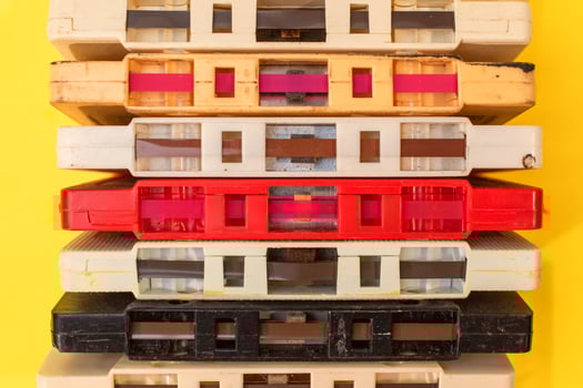 stack of old retro cassette tapes with tape ends showing on yellow background photo