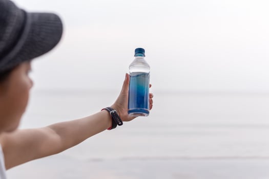 Woman holding bottle mineral water in her hand on the beach. photo