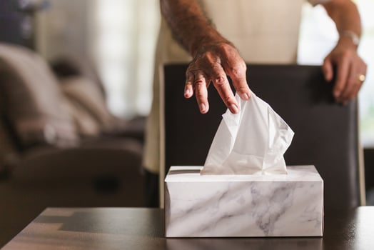 Senior man hand picking up tissue paper from tissue box on dinner table. photo
