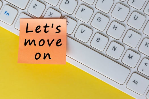 Let's move on text on orange sticky note on top of white keyboard. photo