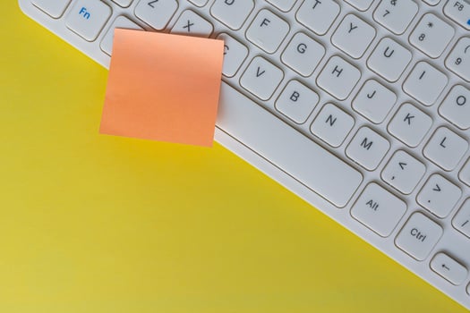 Orange sticky note on top of white keyboard. Flat lay. Copy space. photo