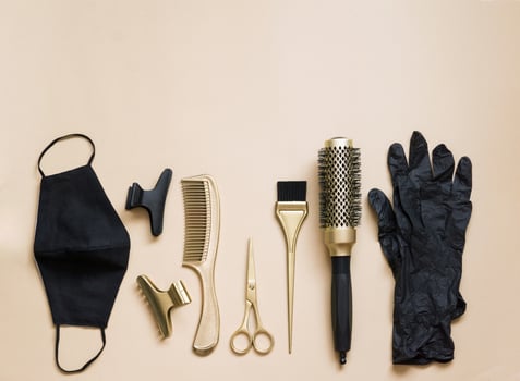 Hairdressing tools on a beige background. Hair salon accessories, scissors, clips, combs, gloves and face mask. photo