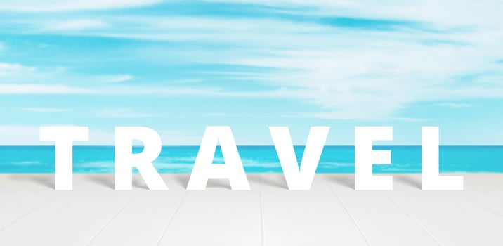 Travel text on white wooden surface front of blue sea and sky photo