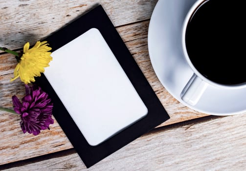 Chalkboard frame with dahlia flowers and white coffee cup on wooden desk. photo