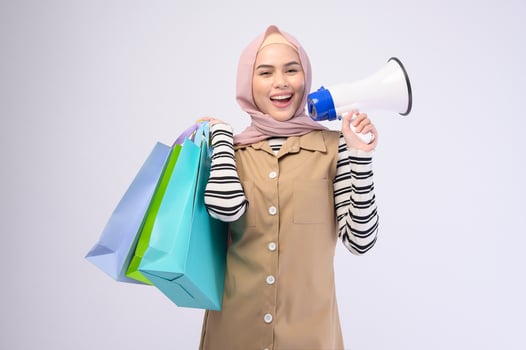 Young beautiful muslim woman in suit holding colorful shopping bags over white background studio photo