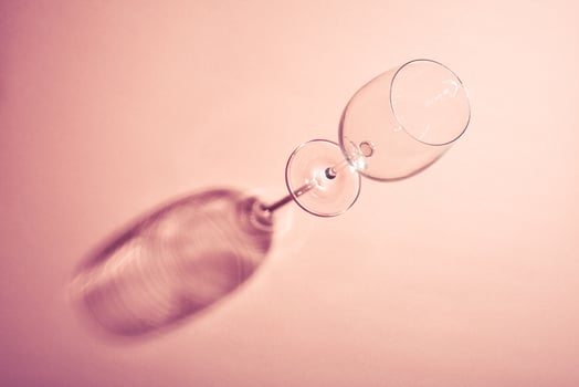 Empty wine glass with creative dark shadow on pink background. photo
