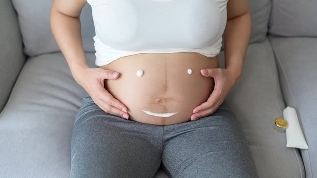 Young pregnant woman applying moisturizing cream on tummy, healthcare and pregnancy care photo
