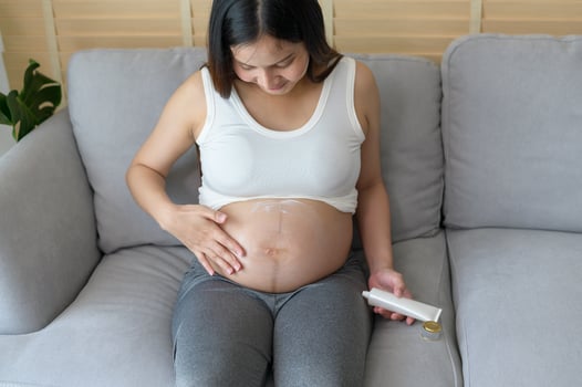 Young pregnant woman applying moisturizing cream on tummy, healthcare and pregnancy care photo