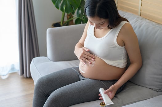 Young pregnant woman applying moisturizing cream on tummy, healthcare and pregnancy care photo
