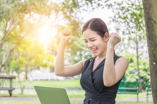 Close up of euphoric young beautiful women celebrating business success reading good news on laptop in the park photo