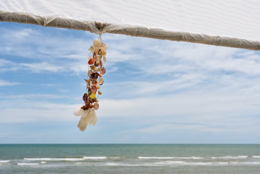Seashell souvenir hanging decoration on wooden gazebo with tropical beach photo
