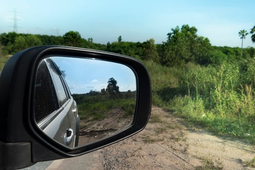 Abstract view of nature beside cars from behind through the mirrors wing of a gray car. photo