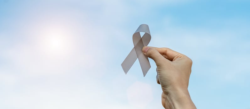 Brain Cancer Awareness month, woman hand holding grey color Ribbon for supporting people living. Healthcare and World cancer day concept photo
