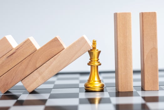 wooden Blocks or Dominoes falling to golden Chess King figure. Business, Risk Management, Solution, economic regression, Insurance photo