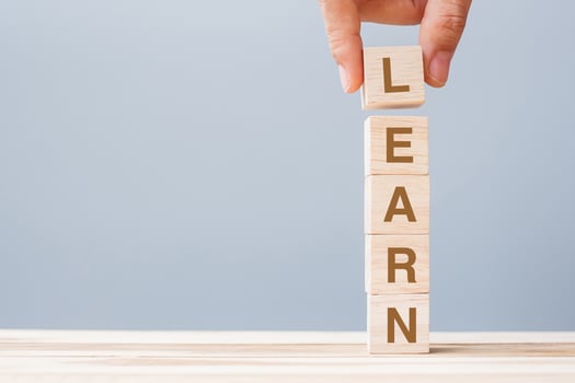 Business man hand holding wooden cube block with LEARN business word on table background. Learning, Education Knowledge, Studying and Wisdom photo