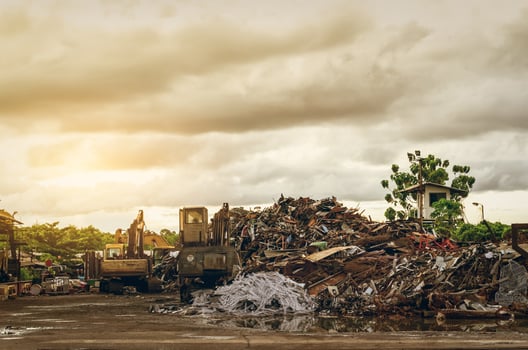Pile of garbage and backhoe at waste depot. Rubbish recycling business. Heap  of plastic waste, wood scrap, and old rusty metal at junkyard near green trees in the forest. Plastic trash for recycle. photo