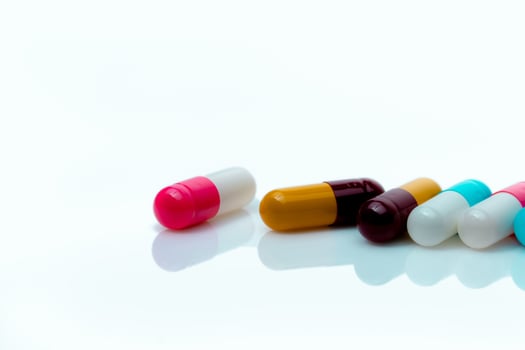 Multi-color antibiotic capsule pills on white background. Antibiotic drug resistance. Prescription drugs. Polypharmacy concept. Pharmacy drugstore product. Pharmaceutical industry. Capsule manufacture photo