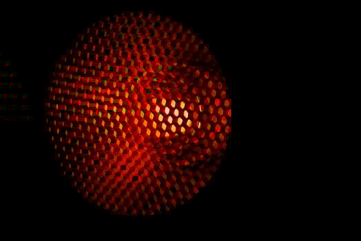 Closeup honeycomb grid texture with red light. Red and dark metal hexagon shaped pattern abstract background. Light modifier equipment. Metal honeycomb. Futuristic pattern. Honey grid cells network. photo
