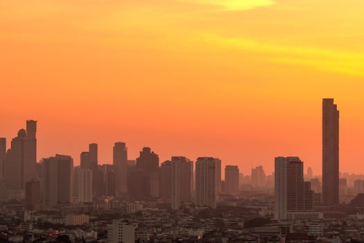 Air pollution. Smog and fine dust of pm2.5 covered city in the morning with orange sunrise sky. Cityscape with polluted air. Dirty environment. Urban toxic dust. Unhealthy air. Urban unhealthy living. photo