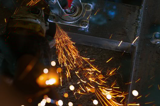Industrial worker using angle grinder cutting metal. Worker working with angle grinder and has orange sparks. Tool for cut and grinding steel. Safety in industrial workplace. Metal factory industry. photo