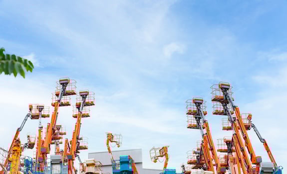 Articulated boom lift. Aerial platform lift. Telescopic boom lift against blue sky. Mobile crane parked at parking area for rent. Hydraulic boom lift at parking lot of crane dealership sale office. photo