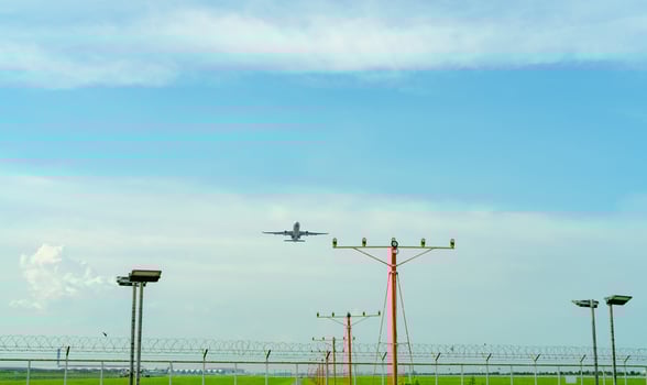 Commercial airplane flying above approach light at the airport. Approach light system concept. Airport runway approach lights. ALS of the airport. Fence for security. Plane take off from the airport. photo