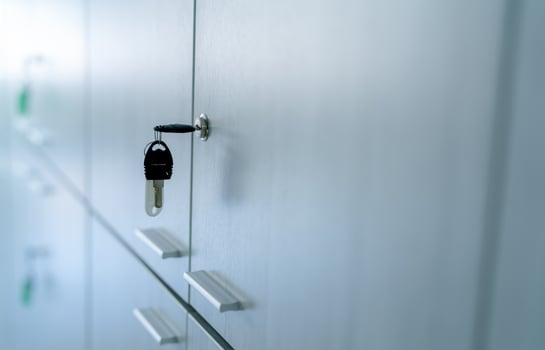 Locker with key in office room. Filing cabinet lock with key for safety and security system in public facility. Secure lock system for document files in business office. White locker door for storage. photo