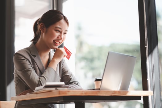 Young woman holding credit card and using laptop computer. Businesswoman working at home. Online shopping, e-commerce, internet banking, spending money, working from home concept photo