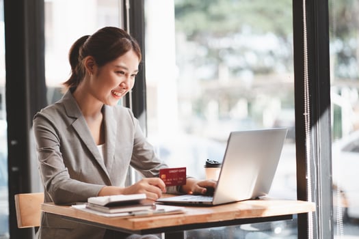 Young woman holding credit card and using laptop computer. Businesswoman working at home. Online shopping, e-commerce, internet banking, spending money, working from home concept photo