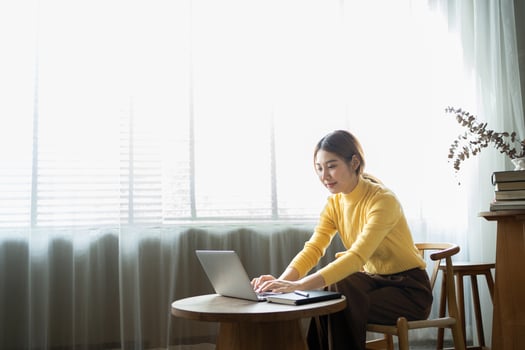 Portrait of beautiful Asian woman sitting indoors at coffee shop restaurant during summer, using smart wireless technology computer laptop and smartphone, relaxing coffee break at cafe restaurant. photo