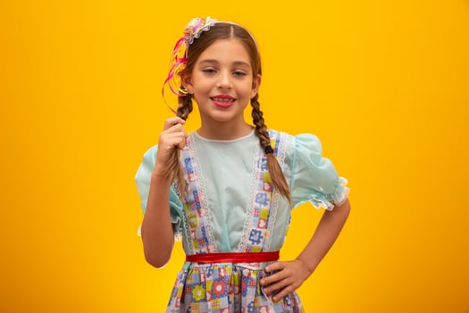 Child in typical clothes of famous Brazilian party called Festa Junina in celebration of Sao Joao. Beautiful girl on yellow background. photo