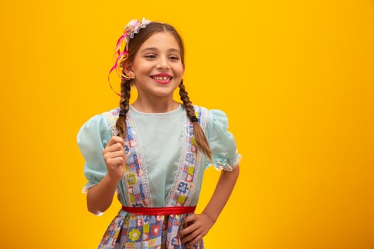 Child in typical clothes of famous Brazilian party called Festa Junina in celebration of Sao Joao. Beautiful girl on yellow background. photo