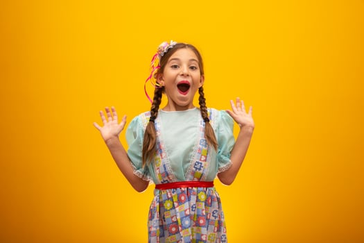 Child in typical clothes of famous Brazilian party called Festa Junina in celebration of Sao Joao. Beautiful girl on yellow background. photo