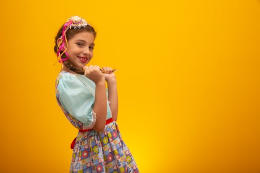 Child in typical clothes of famous Brazilian party called Festa Junina in celebration of Sao Joao. Beautiful girl on yellow background. photo