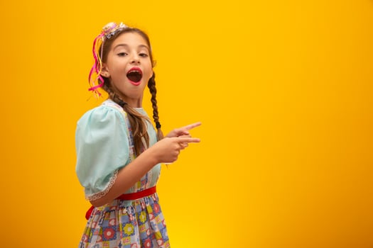 Child in typical clothes of famous Brazilian party called Festa Junina in celebration of Sao Joao. Beautiful girl on yellow background. photo