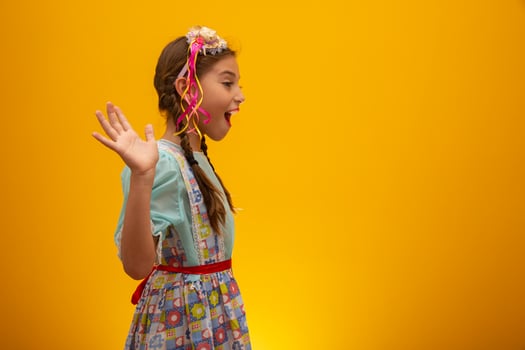 Child in typical clothes of famous Brazilian party called Festa Junina in celebration of Sao Joao. Beautiful girl on yellow background. photo
