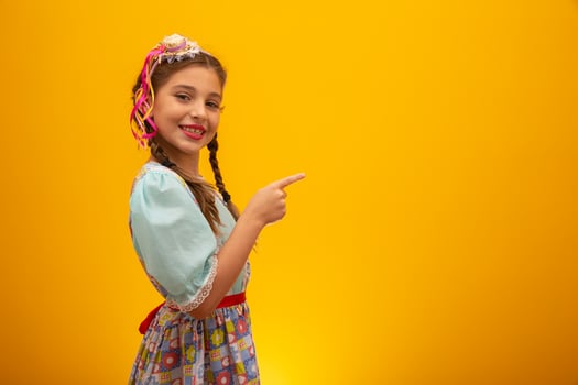 Child in typical clothes of famous Brazilian party called Festa Junina in celebration of Sao Joao. Beautiful girl on yellow background. photo