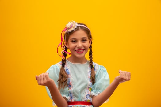 Child in typical clothes of famous Brazilian party called Festa Junina in celebration of Sao Joao. Beautiful girl on yellow background. photo