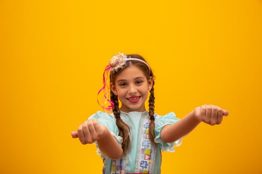Child in typical clothes of famous Brazilian party called Festa Junina in celebration of Sao Joao. Beautiful girl on yellow background. photo