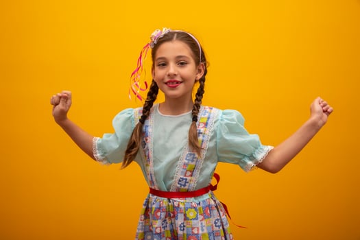 Child in typical clothes of famous Brazilian party called Festa Junina in celebration of Sao Joao. Beautiful girl on yellow background. photo