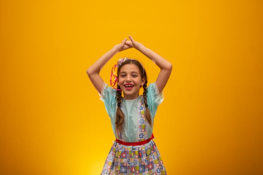 Child in typical clothes of famous Brazilian party called Festa Junina in celebration of Sao Joao. Beautiful girl on yellow background. photo