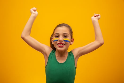 Football supporter, Brazil team. World Cup. Beautiful little girl cheering for her team on yellow background photo
