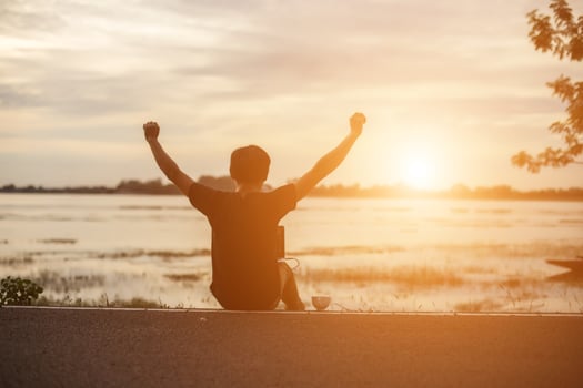 Successful sportsman raising arms on golden sky back lighting sunset summer after cross running. Fitness male athlete with arms up celebrating goals after sport exercising and working out outdoors. photo