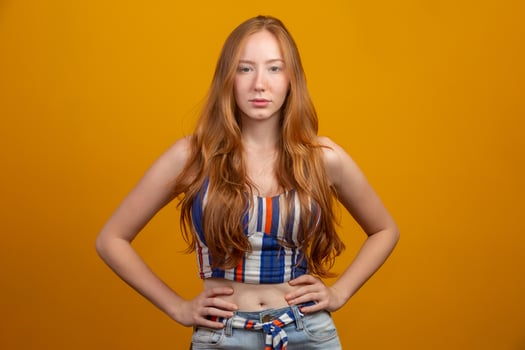 Portrait of beautiful cheerful redhead girl with flying hair smiling laughing looking at camera over yellow background. photo