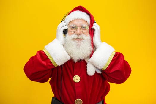 Santa Claus dancing on yellow background. Santa Claus wearing headphones. Christmas party concept with music. photo