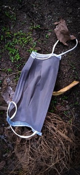 An unused-disposable grey face mask thrown away on the ground. photo