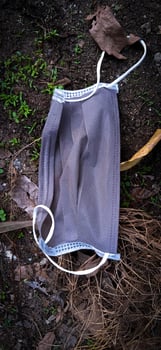 An unused-disposable grey face mask thrown away on the ground. photo