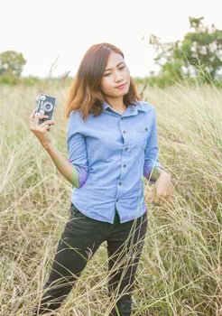 Vintage of beautiful women photography standing hand holding retro camera with sunrise,dream soft style photo