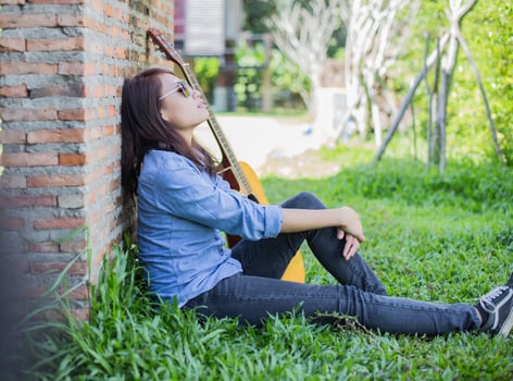 Hipster man playing guitar for his girlfriend outdoor against brick wall, enjoying together. photo