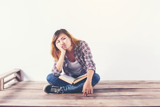 Young hipster woman holding books and pointing up on isolated white background. photo